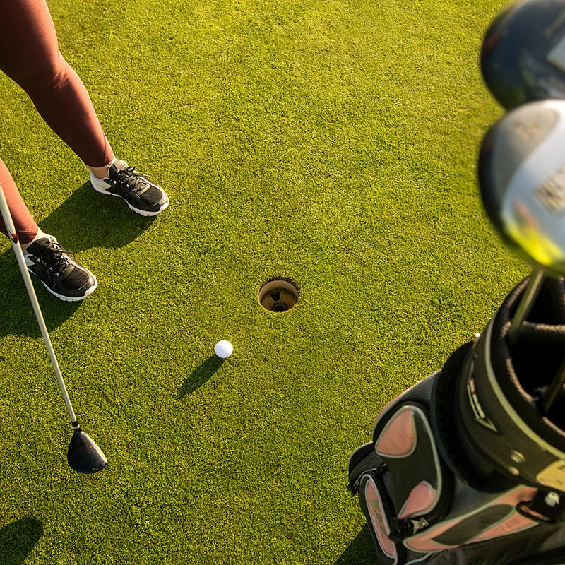 Golferin auf Golfplatz mit Golfzubehör